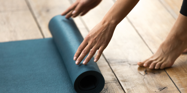 Une personne déroule un tapis de yoga.