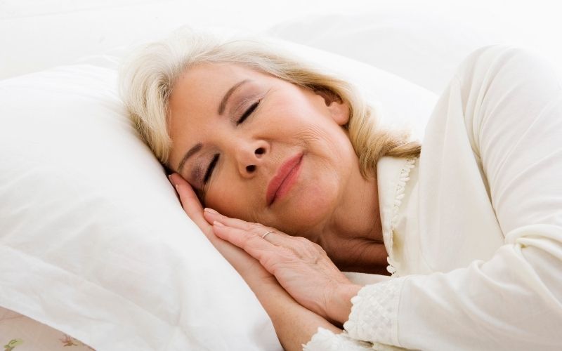 Femme âgée dormant paisiblement sur un lit.