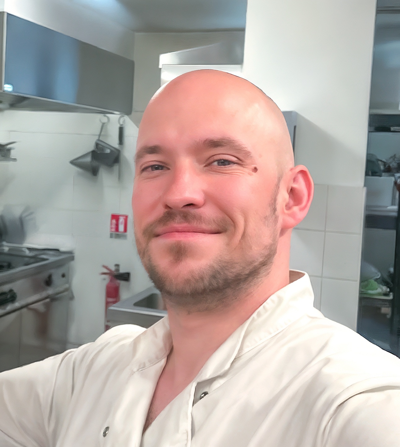 Chef souriant dans une cuisine professionnelle.