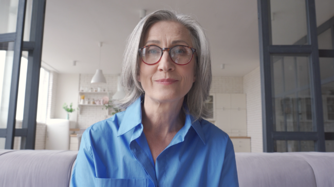 Donna anziana con occhiali e camicia blu.