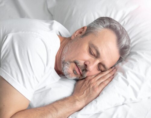 Uomo anziano dorme serenamente su un cuscino.