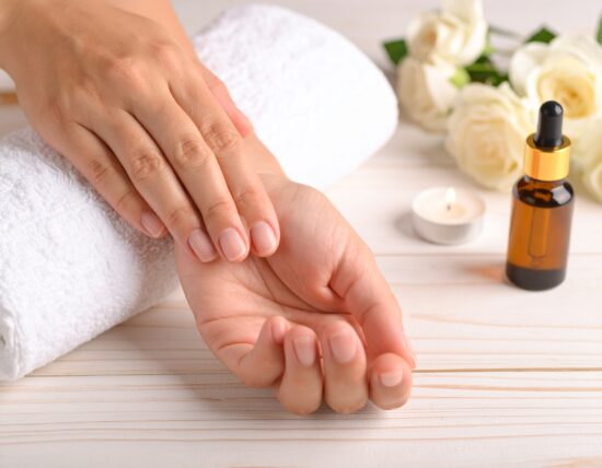 Händemassage mit Ölen und dekorativen Elementen.