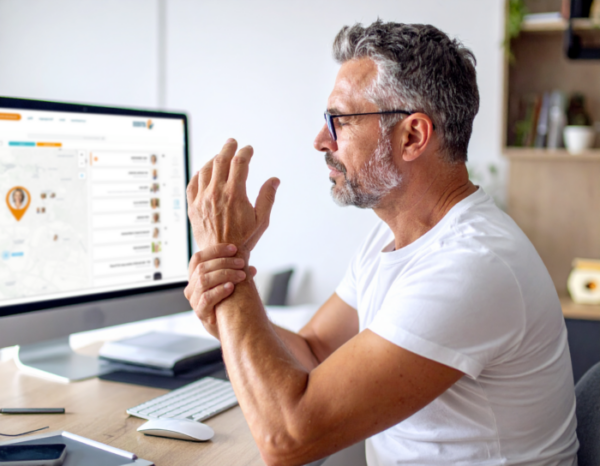 Uomo al computer con dolori alle mani.